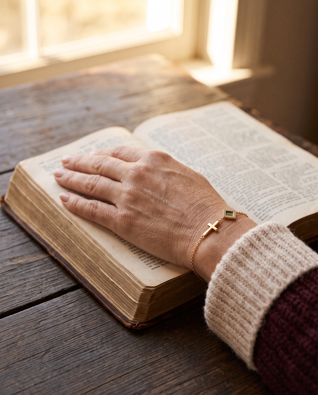 A woman's hand resting on an open Bible, wearing The Cross Bracelet