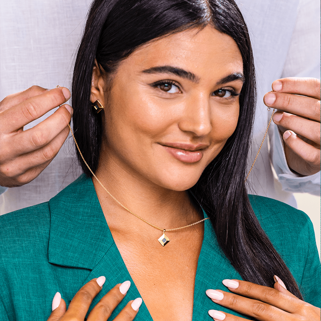 Woman smiling while a necklace is being placed on her.